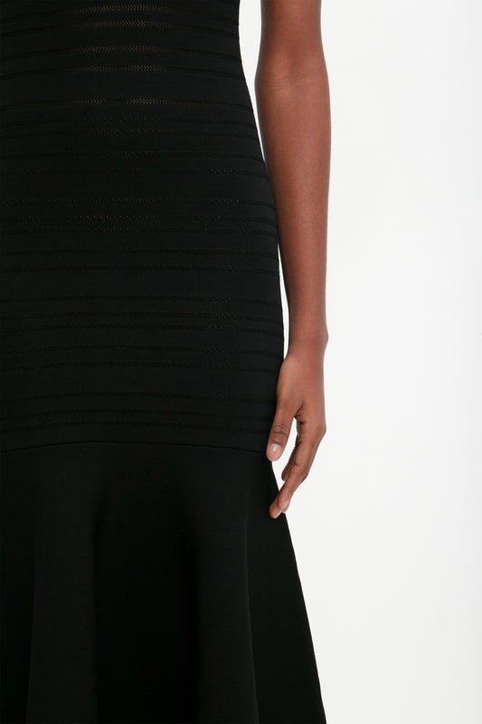Close-up of a person in a Victoria Beckham Frame Detail Sleeveless Dress In Black, focusing on the side of the torso and arm against a white background.