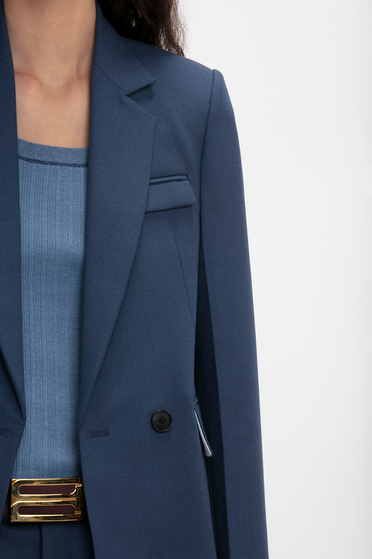 Close-up of a woman wearing a Victoria Beckham Shrunken Double Breasted Jacket In Heritage Blue and a matching ribbed top, partially visible with a focus on the blazer's detail.