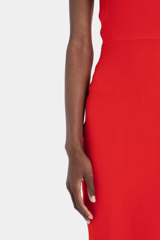 Close-up of a woman's side and arm in a Victoria Beckham bright red fitted T-shirt dress, isolated on a white background. The focus is on her arm and the fabric texture of the dress.