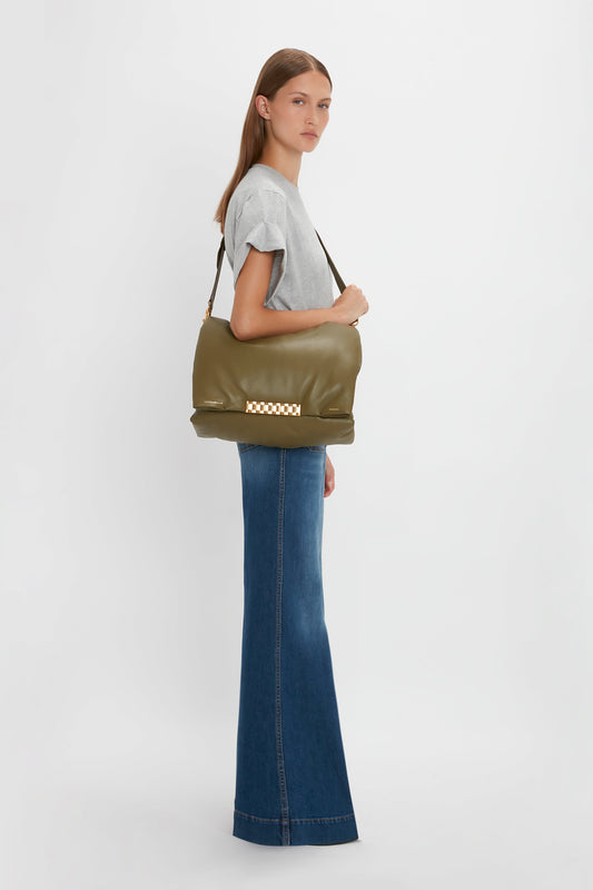 A woman in a gray t-shirt and Alina Jean in Dark Vintage Wash, carrying a large olive green shoulder bag, standing against a white background.