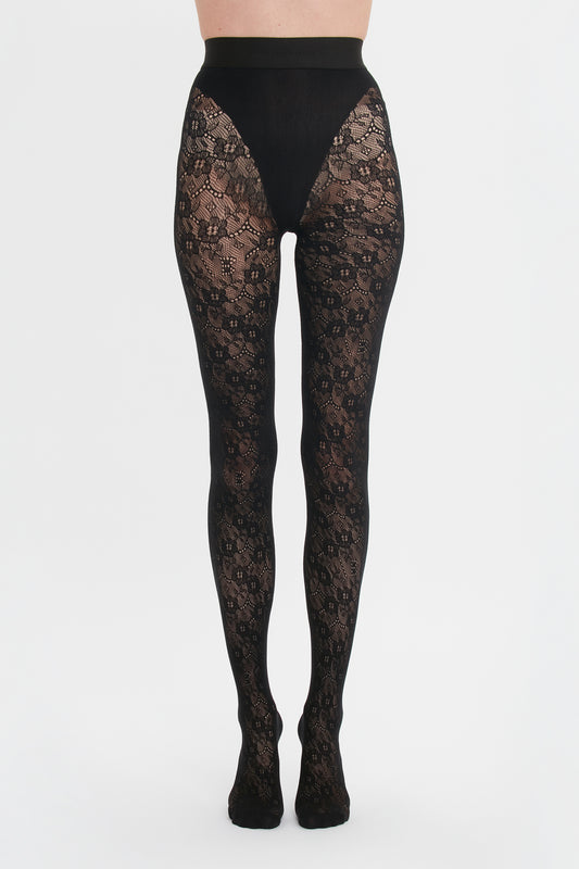 A person wearing ornate Victoria Beckham Exclusive VB Monogram Lace Tights in Black against a white background.