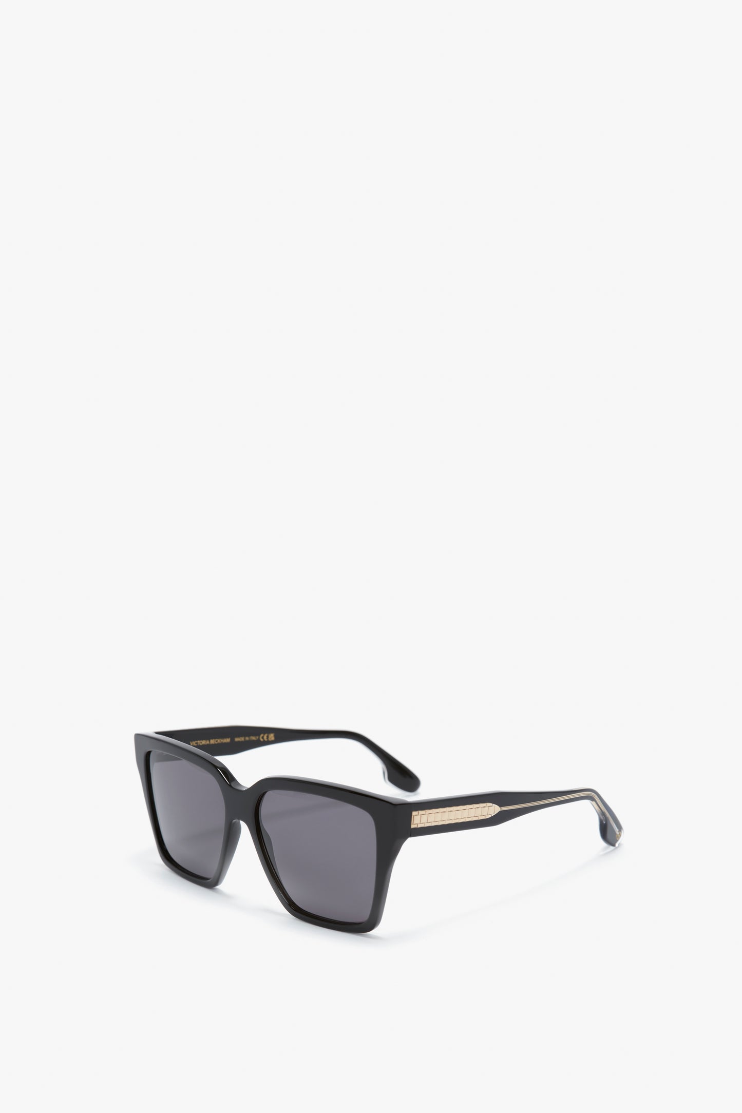A pair of Victoria Beckham Soft Square Frame Sunglasses In Black, featuring dark tinted lenses and gold detailing on the temples, set against a plain white background.