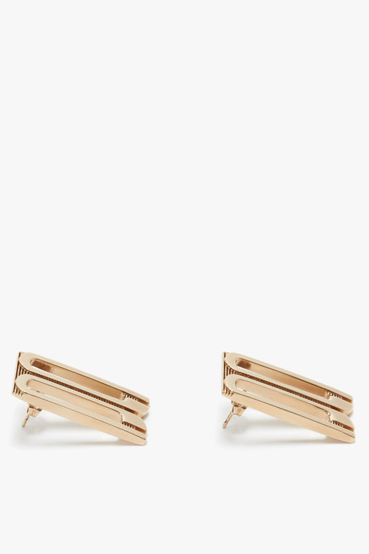A pair of Exclusive Frame Stud Earrings in Gold by Victoria Beckham with a simple, elongated geometric design on a white background.