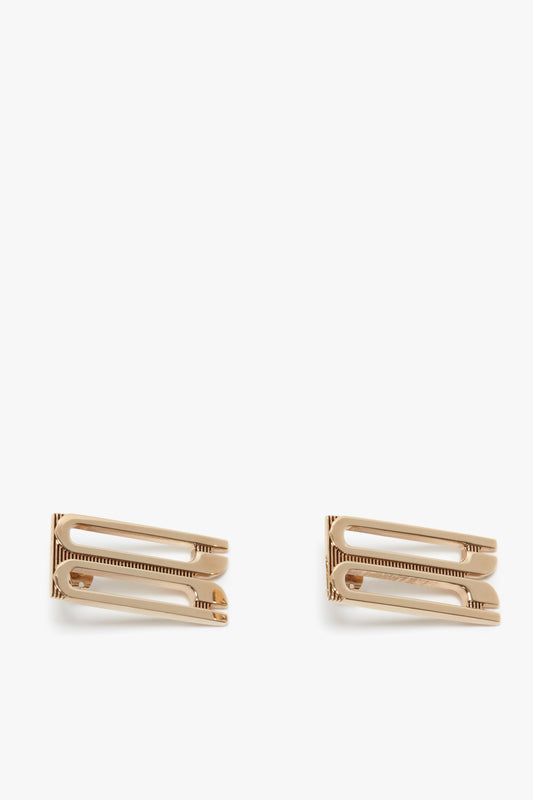 Two Exclusive Frame Stud Earrings In Gold with comb teeth, isolated on a white background by Victoria Beckham.