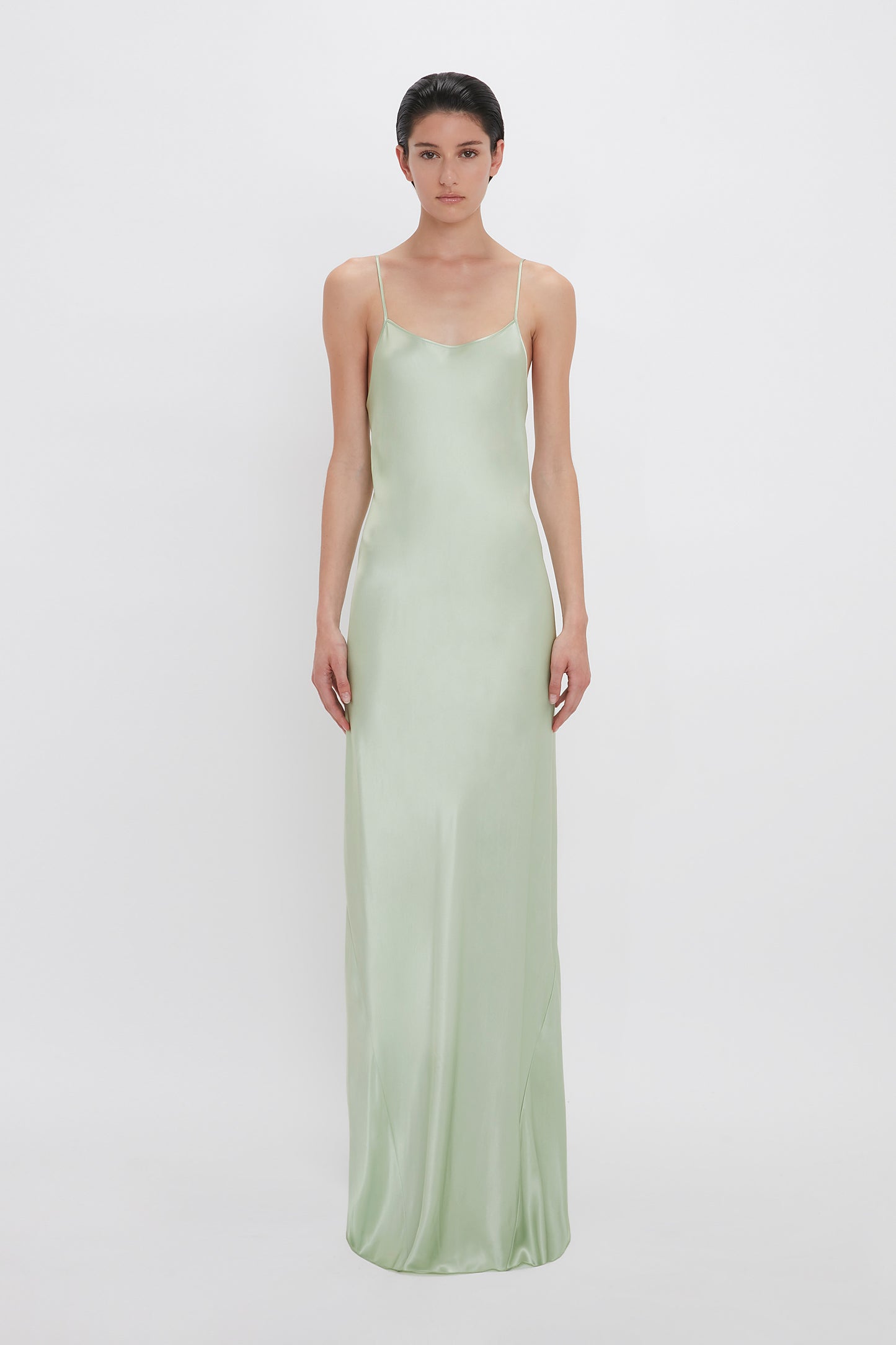 Woman in an Exclusive Low Back Cami Floor-Length Dress In Jade by Victoria Beckham, standing against a white background.
