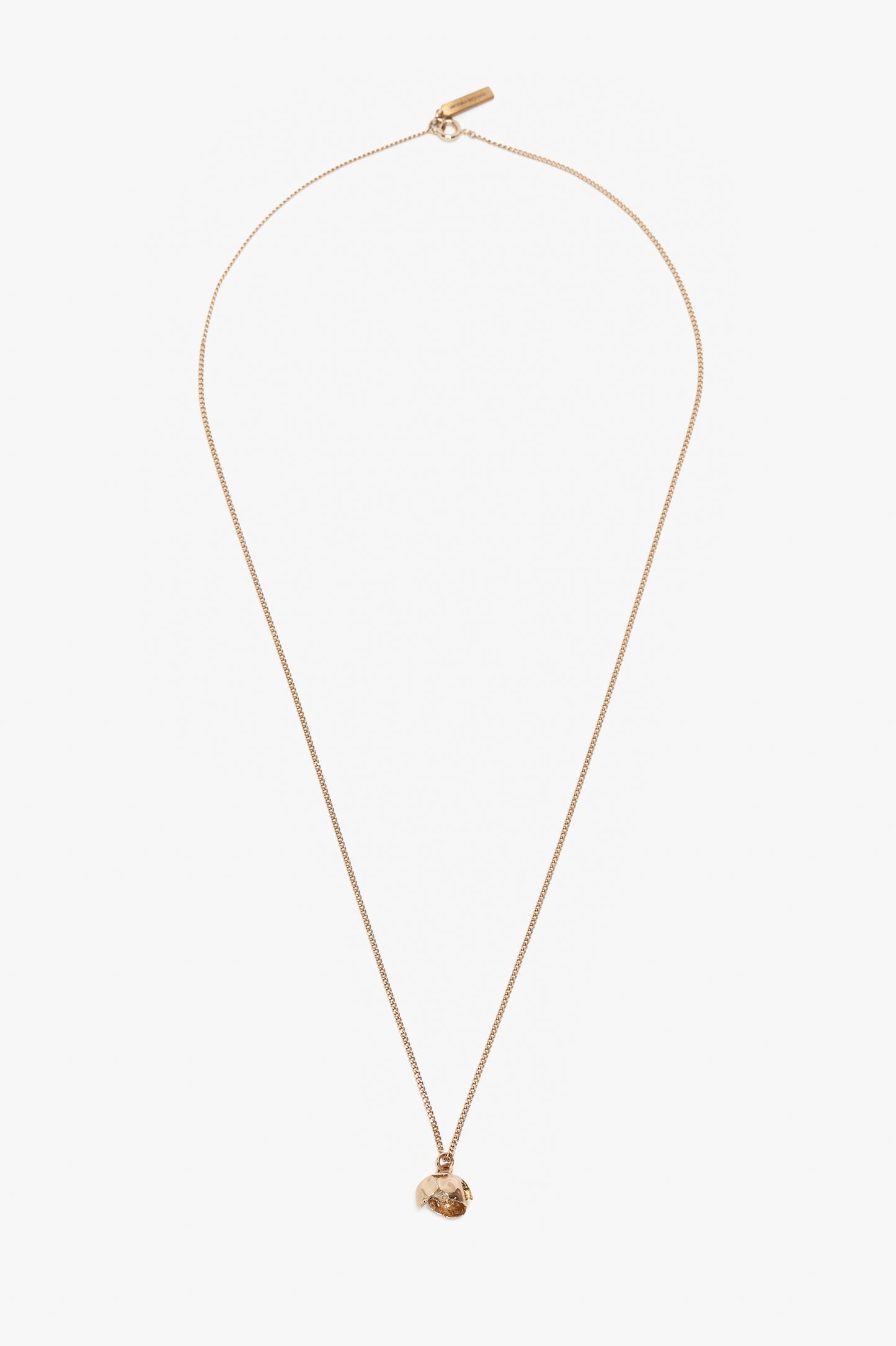 A thin Exclusive Camellia Flower Necklace In Gold, handcrafted in Italy by Victoria Beckham, featuring a small, irregularly shaped pendant on a white background.