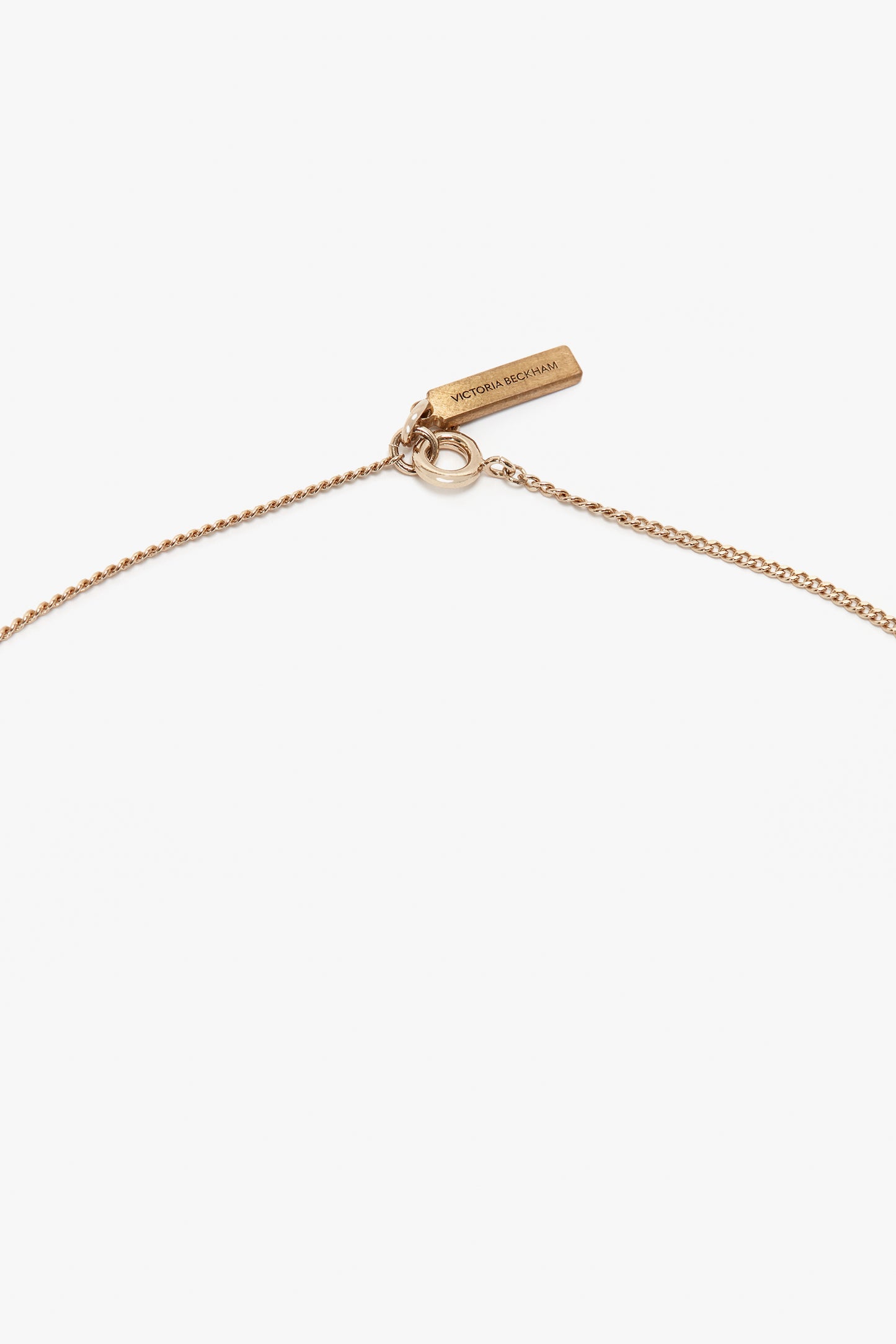 A delicate gold necklace, handcrafted in Italy, with a small rectangular tag inscribed with "Victoria Beckham," featuring a minimalist chain and clasp, the **Exclusive Camellia Flower Necklace In Gold**.