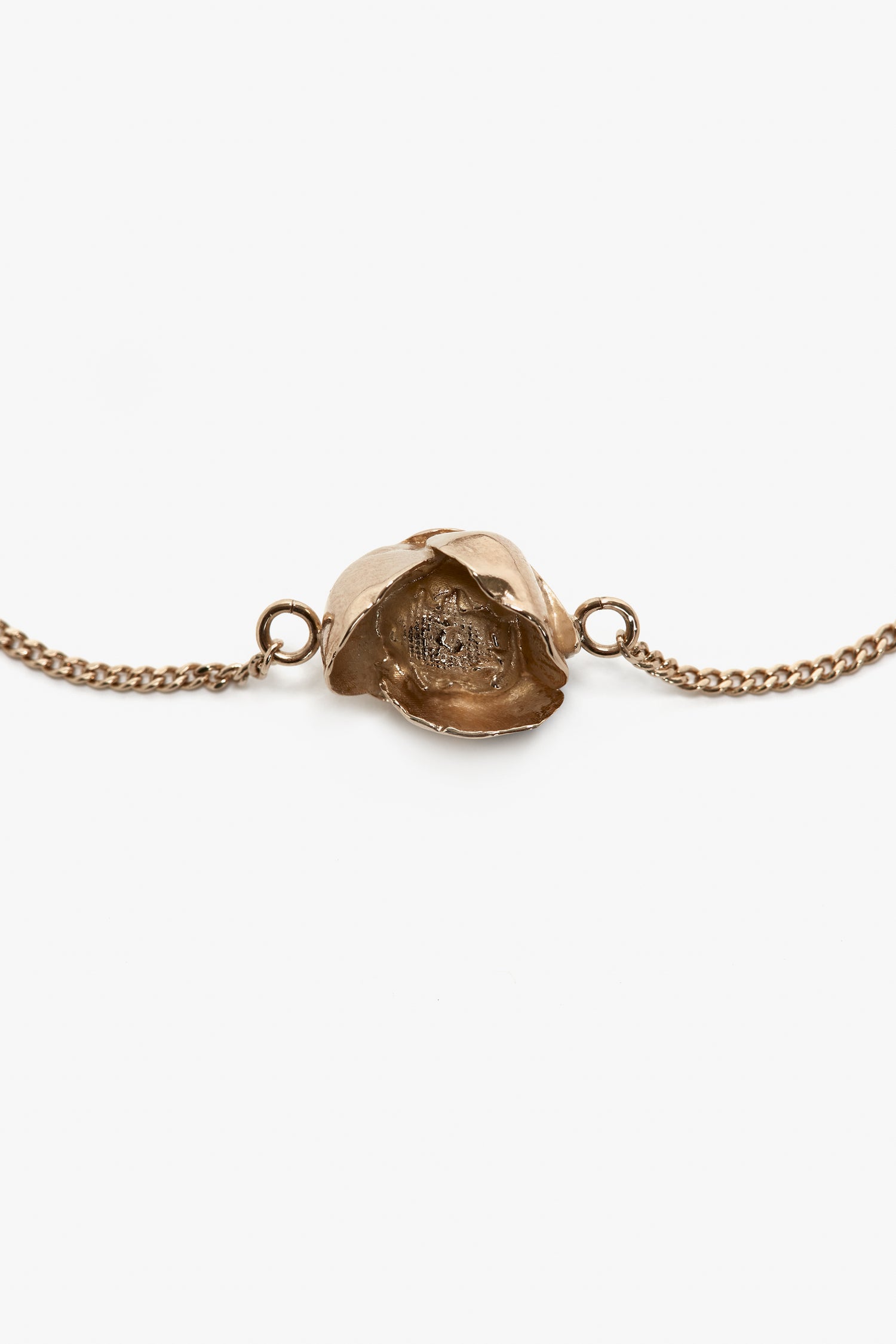 The Victoria Beckham Exclusive Camellia Flower Bracelet In Gold is a gold brushed brass chain bracelet with an adjustable chain, featuring a central flower-shaped pendant with intricate petal details.