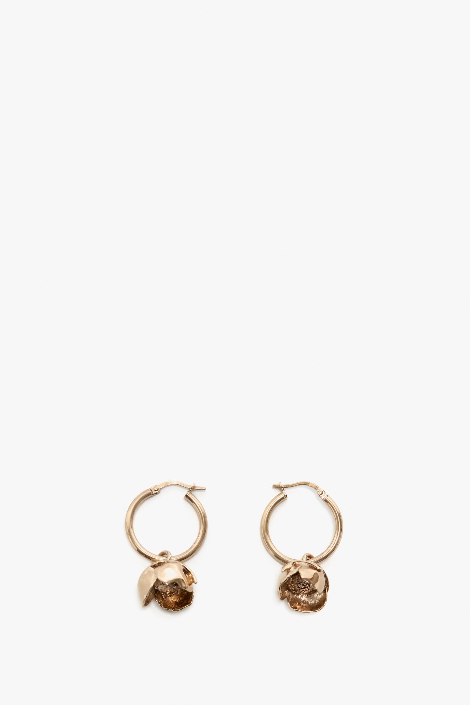 A pair of Exclusive Camellia Flower Hoop Earrings In Gold by Victoria Beckham with small, textured pendants, isolated on a white background.
