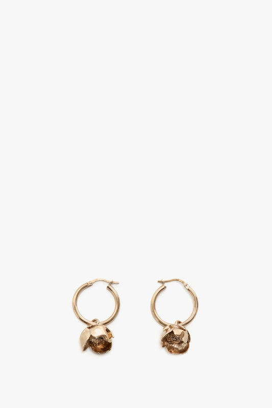 A pair of Exclusive Camellia Flower Hoop Earrings In Gold by Victoria Beckham with small, textured pendants, isolated on a white background.