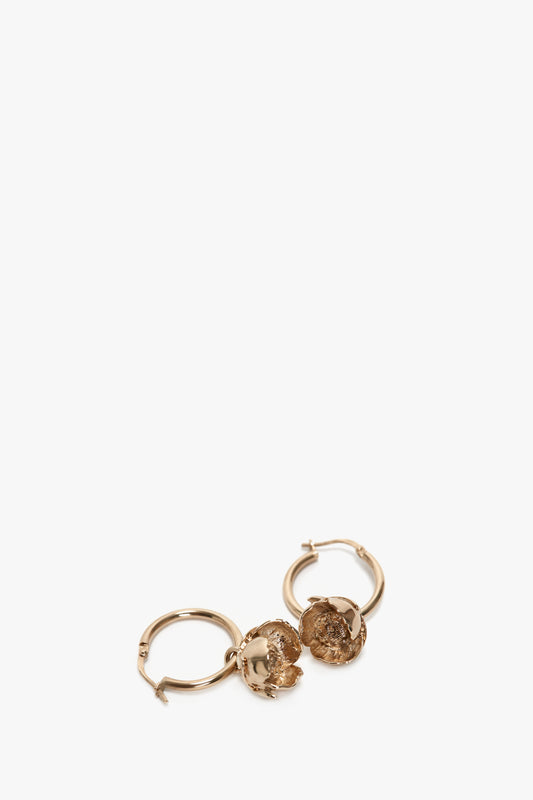 A pair of small gold-plated brass hoop earrings with intricate, round Exclusive Camellia Flower charms attached, isolated on a white background by Victoria Beckham.