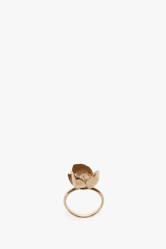 A handcrafted in Italy gold ring featuring a decorative element resembling a small, open Exclusive Camellia Flower against a white background by Victoria Beckham.