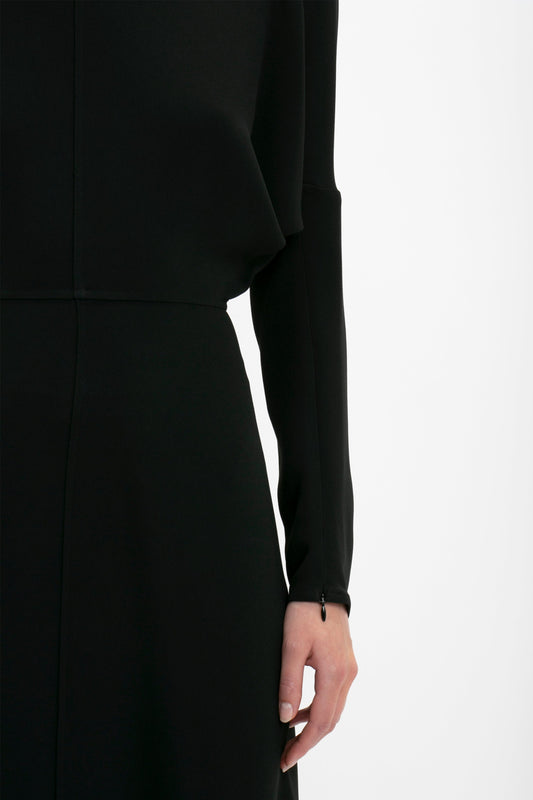 Close-up of a woman wearing a black Victoria Beckham Dolman Sleeve Midi dress, focusing on her arm and side, against a white background.