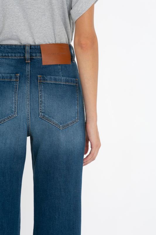 Rear view of a person wearing Victoria Beckham Alina Jean blue jeans with a brown leather brand patch on the waistband. The focus is on the jeans and the patch.