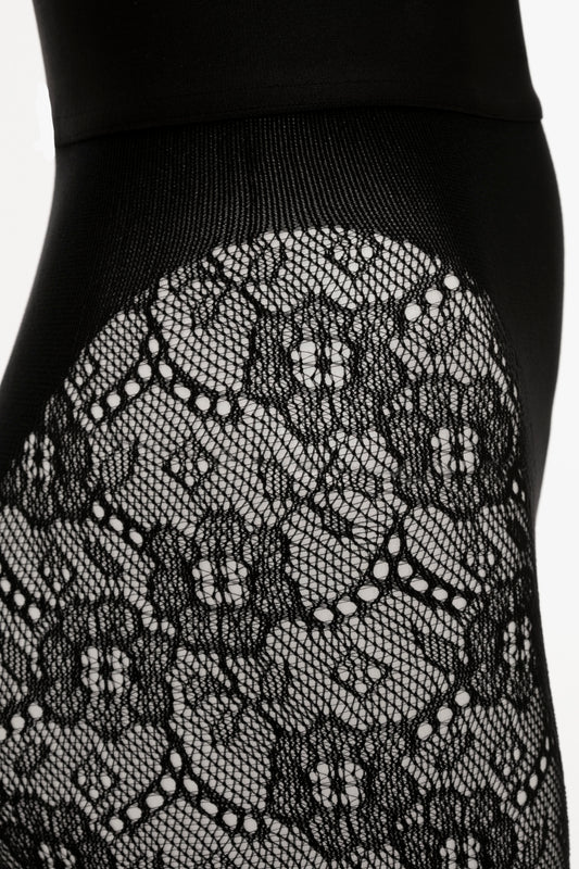 Close-up of black Victoria Beckham Monogram Lace Tights with floral patterns, showcasing detailed textile design.