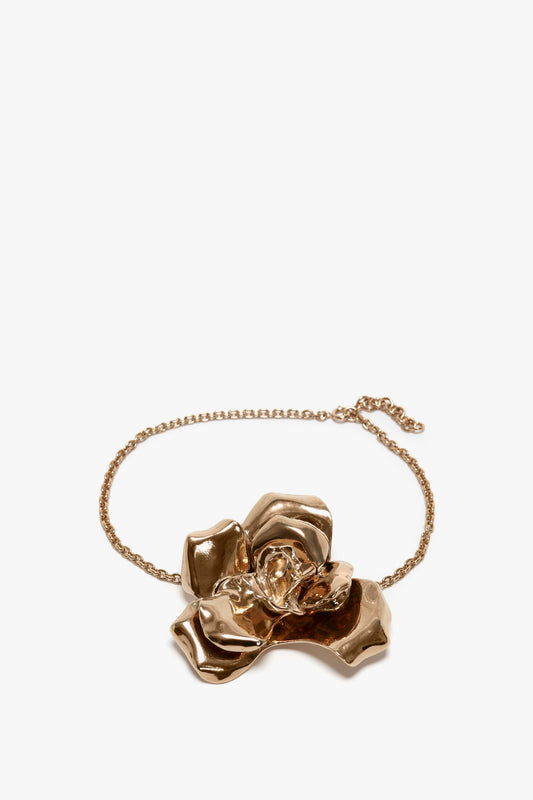 A golden bracelet featuring a large, gold brushed brass flower pendant on a white background by Victoria Beckham.