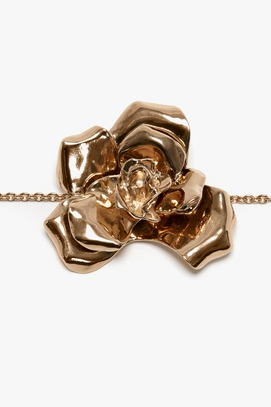 A polished rose-gold Exclusive Flower Bracelet in Gold pendant with detailed petals and a central gem, attached to an adjustable chain, isolated on a white background by Victoria Beckham.