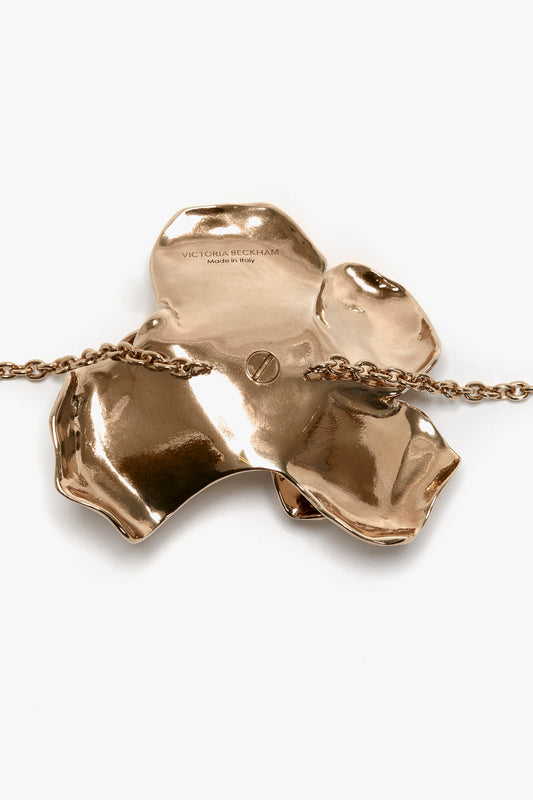 Exclusive Flower Bracelet In Gold from Victoria Beckham, with a glossy finish and engraved designer name, suspended from an adjustable chain, displayed on a white background.