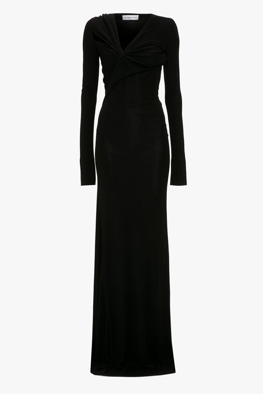 Long-sleeve black evening gown with a v-neckline and draped, twisted detailing at the waist, displayed on a white background, Victoria Beckham's Tie Detail Floor-Length Dress in Black.
