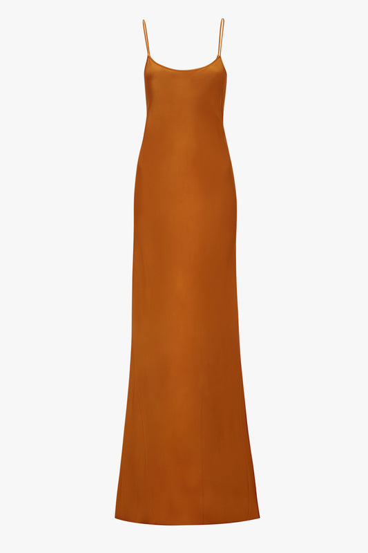 An elegant Victoria Beckham floor-length cami dress in ginger with thin straps and a smooth, straight silhouette, displayed against a white background.