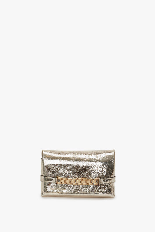 A metallic silver Victoria Beckham Mini Chain Pouch with a decorative golden clasp, isolated on a white background.