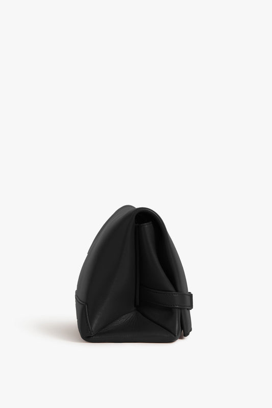Side view of a Victoria Beckham black leather chain pouch bag on a white background.