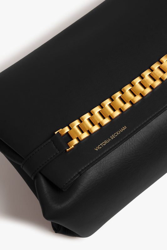 Close-up of a black Victoria Beckham Chain Pouch Bag in Black Leather with prominent gold-tone hardware.