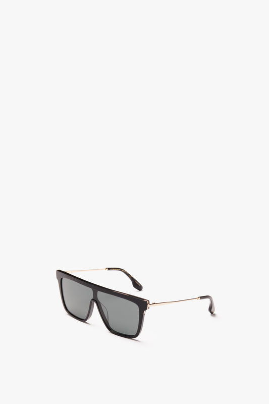 A pair of Rectangular Shield Sunglasses In Black with a thin gold frame, isolated on a white background, featuring the Victoria Beckham Eyewear design.