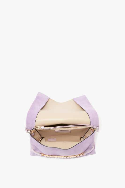 A Victoria Beckham Lilac Suede Chain Pouch with Strap featuring a gold chain detachable strap and open top revealing a beige interior, set against a white background.