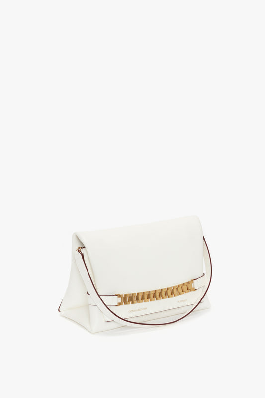 White Victoria Beckham Nappa leather chain pouch with strap clutch with gold zipper and embellishments on a white background.