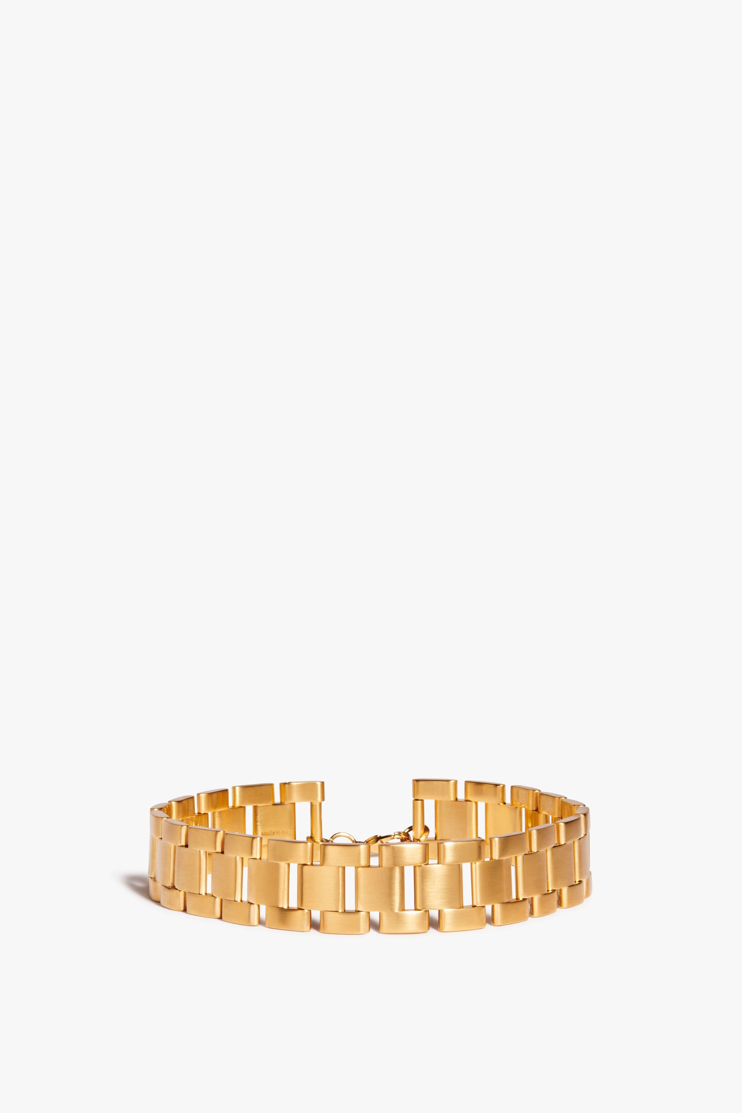 A Victoria Beckham Watch Chain Choker In Gold, reminiscent of a watch-inspired chain, features a broad, flat, and shiny surface against a plain white background.