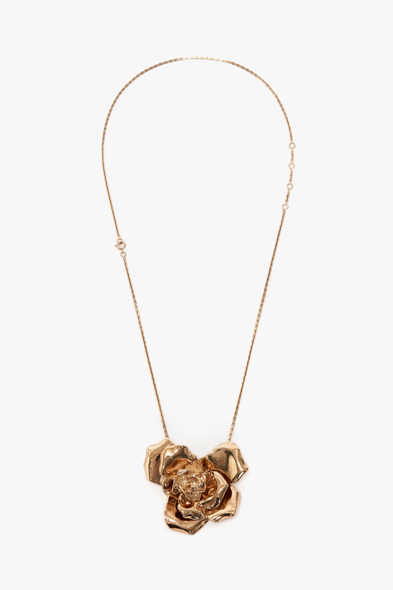 The Victoria Beckham Exclusive Flower Necklace In Gold, featuring an intricately designed rose pendant, adds sophistication to any outfit.