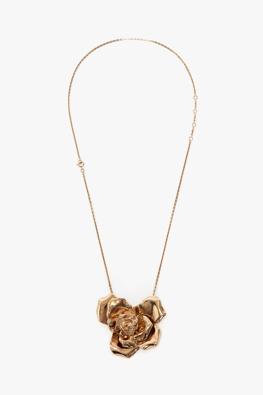 The Victoria Beckham Exclusive Flower Necklace In Gold, featuring an intricately designed rose pendant, adds sophistication to any outfit.
