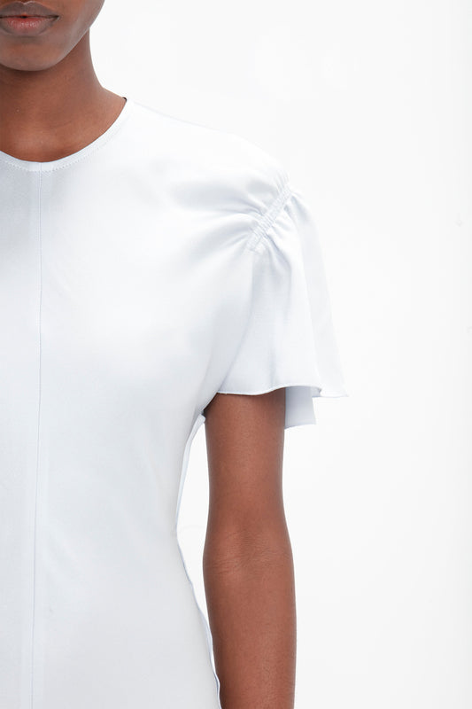 A person wearing the Victoria Beckham Gathered Sleeve Midi Dress In Ice is shown from the shoulders to just above the elbow against a plain white background.