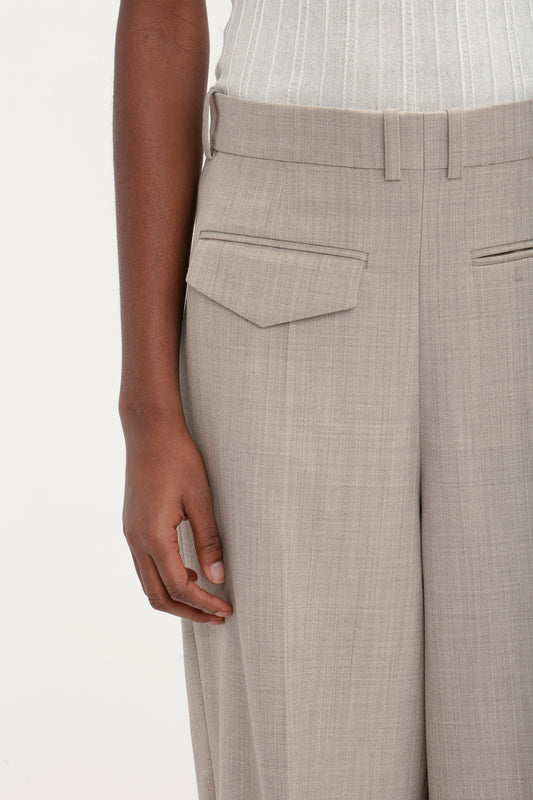 A person wearing a light gray sleeveless top and the Victoria Beckham Reverse Front Trouser in Sesame is shown from the waist down, showcasing a contemporary silhouette.