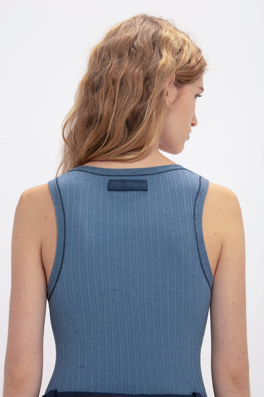 A person with long, wavy hair, seen from the back, wearing a Victoria Beckham Fine Knit Micro Stripe Tank In Heritage Blue. The top has a small label near the neckline.