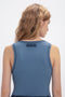 A person with long, wavy hair, seen from the back, wearing a Victoria Beckham Fine Knit Micro Stripe Tank In Heritage Blue. The top has a small label near the neckline.