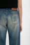 Close-up of a person wearing Victoria Beckham Relaxed Straight Leg Jean In Antique Indigo Wash showing a detailed view of the back pocket and waistband against a white background.