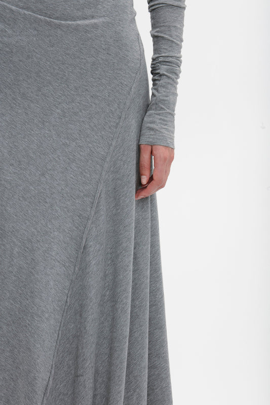 Close-up of a person's hand resting on the side of a gray Long Sleeve Circle Neck Dress In Grey Marl by Victoria Beckham made from a super-soft cotton-jersey blend. The background is plain white.