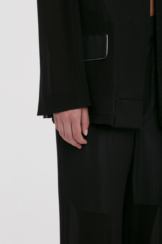 Close-up of a person's hand in a Victoria Beckham Fold Detail Tailored Jacket In Black pocket, accentuating elegant details and fabric texture.