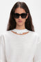 Wearing Victoria Beckham eyewear, a person with long dark hair sports large Soft Square Frame Sunglasses In Black and a white top with a cut-out detail and a tag on the collar.