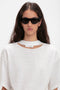 A person with long dark hair and Layered Lens Visor Sunglasses In Black from Victoria Beckham wears a white T-shirt with a small cutout near the neckline.