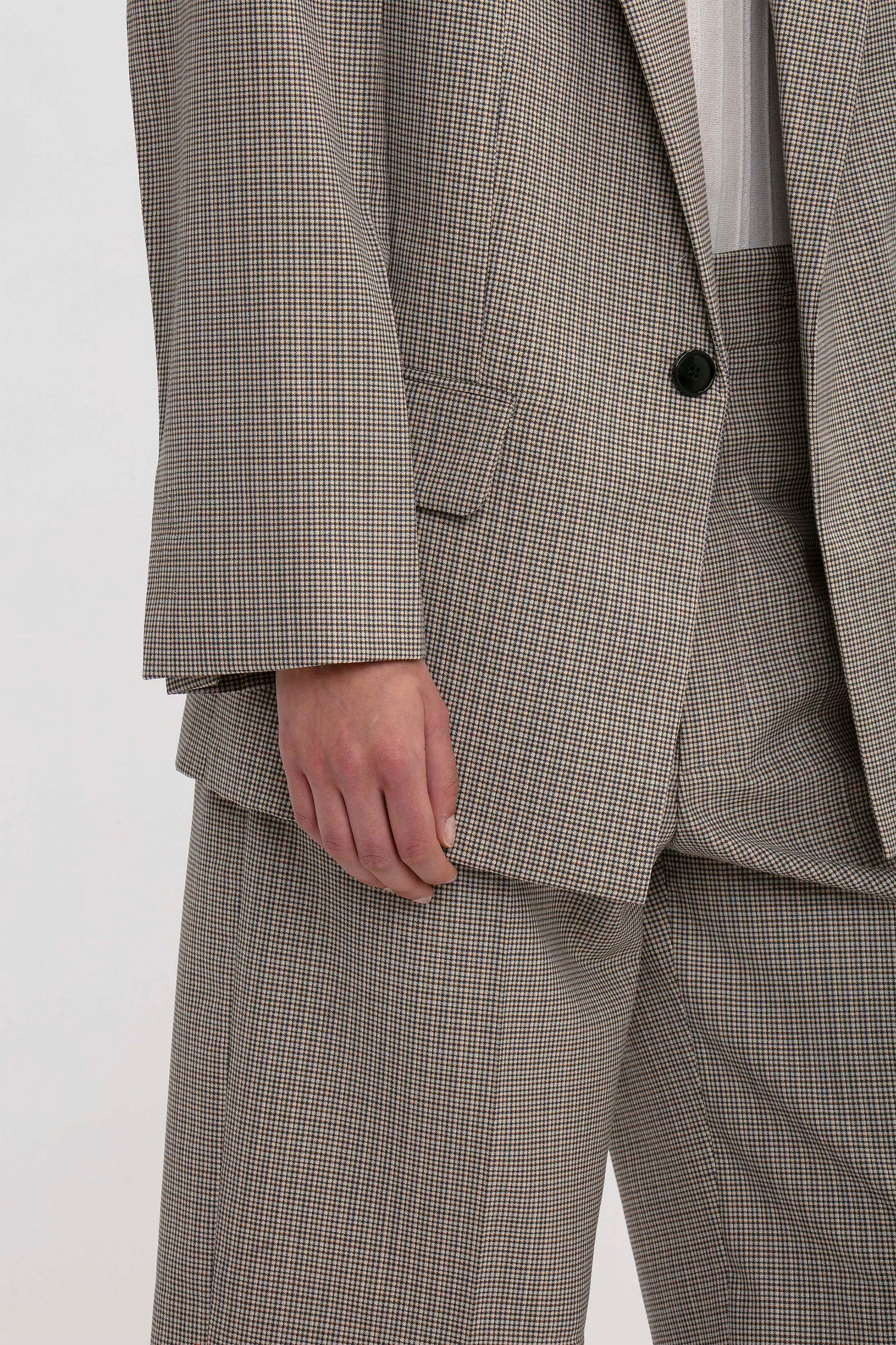 Close-up of a person wearing the Victoria Beckham Peak Lapel Jacket In Multi and matching pants with a contemporary aesthetic; only the torso and part of the arm are visible.