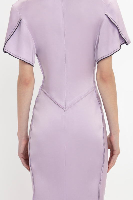 Back view of a person wearing a Gathered V-Neck Midi Dress In Petunia by Victoria Beckham with short, structured sleeves, visible seam stitching, and waist-defining pleat details.