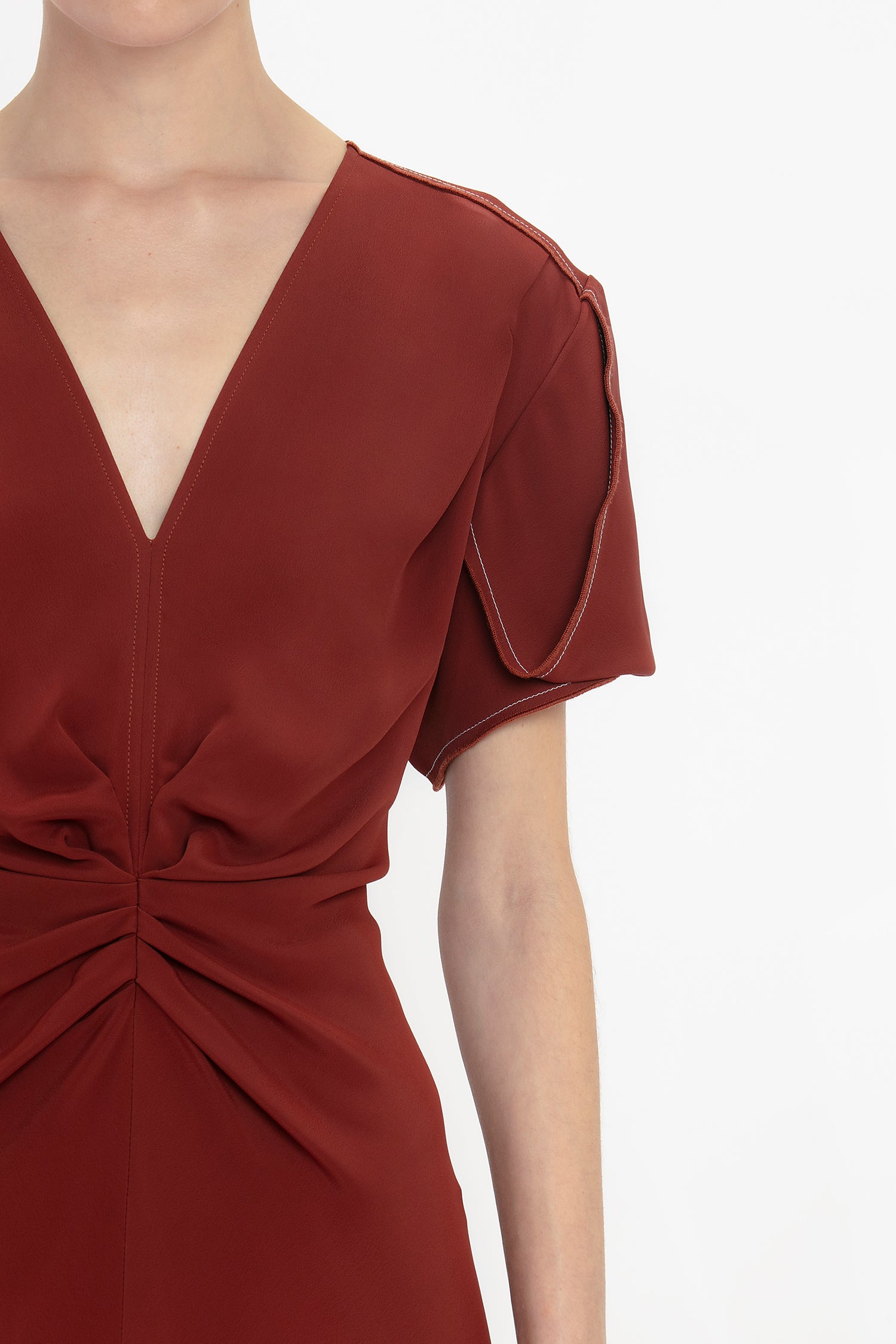 Person wearing a rust-colored Gathered V-Neck Midi Dress In Russet by Victoria Beckham with figure-flattering stretch fabric and waist-defining pleat detail.