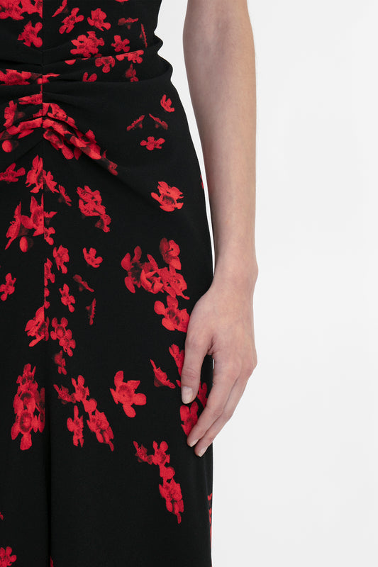 A person wearing a Victoria Beckham Gathered Waist Midi Dress In Sci-Fi Black Floral, their right hand resting by their side.