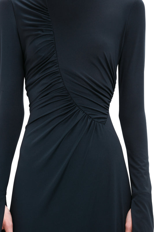 Close-up of a Victoria Beckham Ruched Detail Floor-Length Gown In Midnight with long sleeves and a gathered, ruched detail running diagonally across the torso from shoulder to opposite hip, exuding understated glamour.