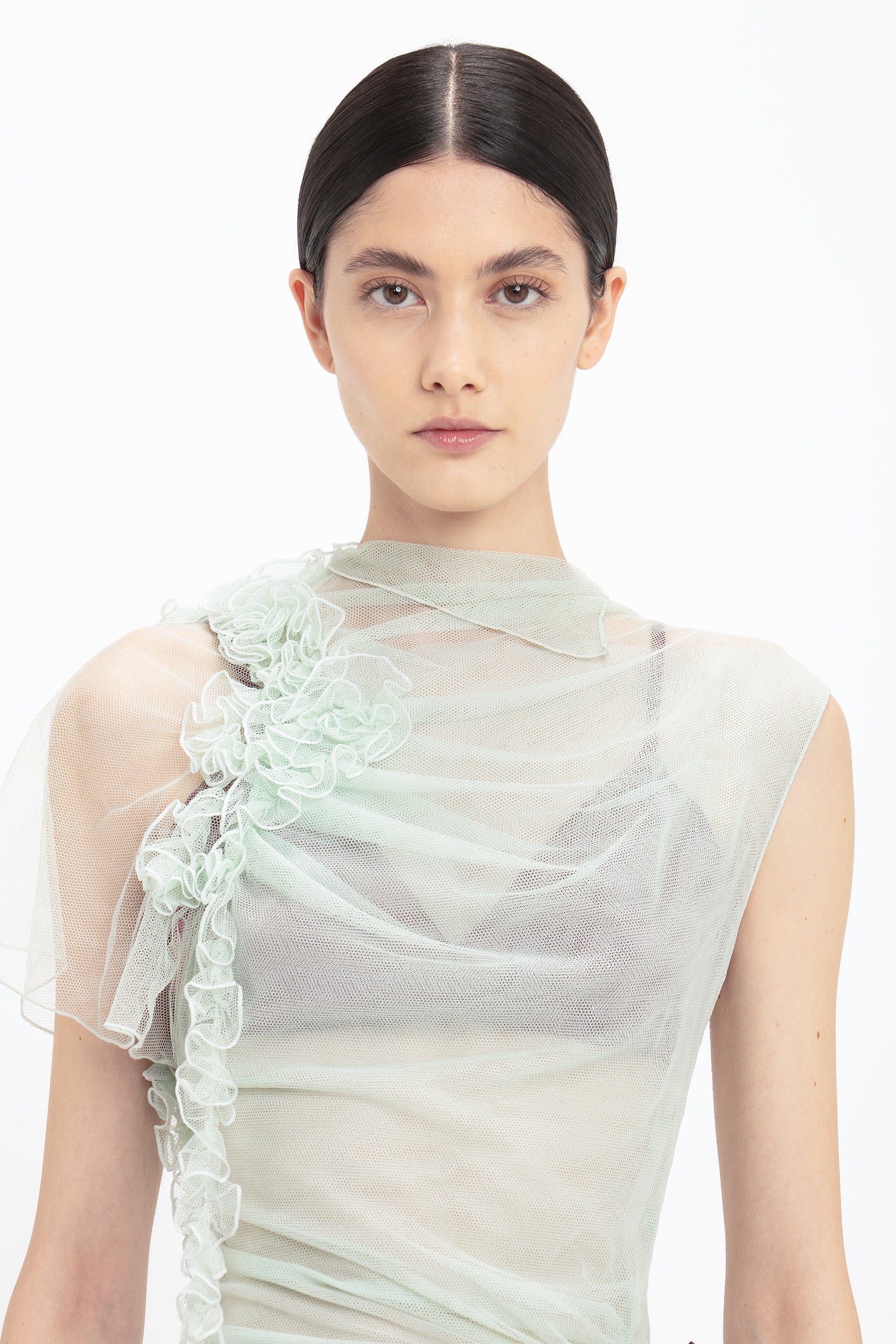 A woman with dark hair is wearing a Victoria Beckham Gathered Tulle Detail Floor-Length Dress In Jade. She is looking directly at the camera with a neutral expression against a plain background. For more stunning designs, visit VictoriaBeckham.com.