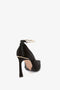 A Victoria Beckham Pointy Toe Pump in Black Satin with a gold metal ankle bracelet is shown from the back on a white background, featuring an elegant 100mm heel.