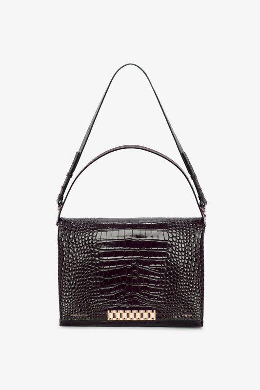 The Jumbo Chain Pouch Bag In Chocolate Croc-Effect Leather by Victoria Beckham with a crocodile texture, a single top handle, and a gold-tone rectangular clasp on the front offers versatile styling for any occasion.